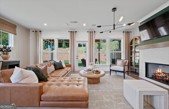 living room with a fireplace, light wood-type flooring, and a notable chandelier