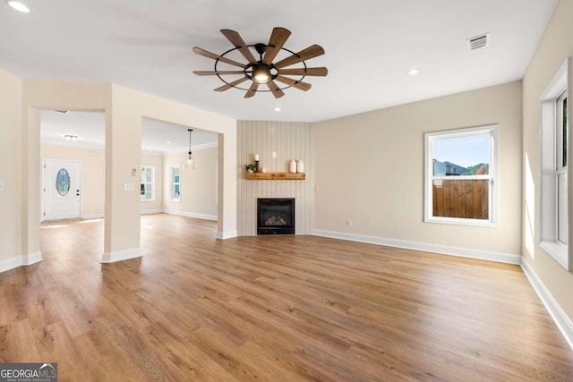 unfurnished living room featuring a fireplace, light hardwood / wood-style flooring, and ceiling fan