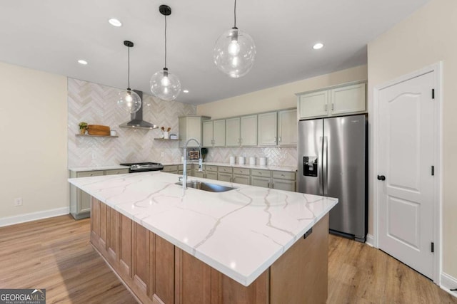 kitchen with light stone counters, stainless steel appliances, a spacious island, sink, and light hardwood / wood-style floors