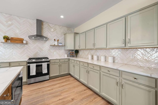 kitchen featuring decorative backsplash, light wood-type flooring, stainless steel range, black microwave, and wall chimney range hood