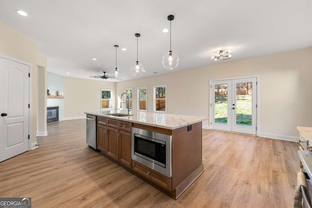 kitchen with ceiling fan, sink, stainless steel appliances, pendant lighting, and a kitchen island with sink