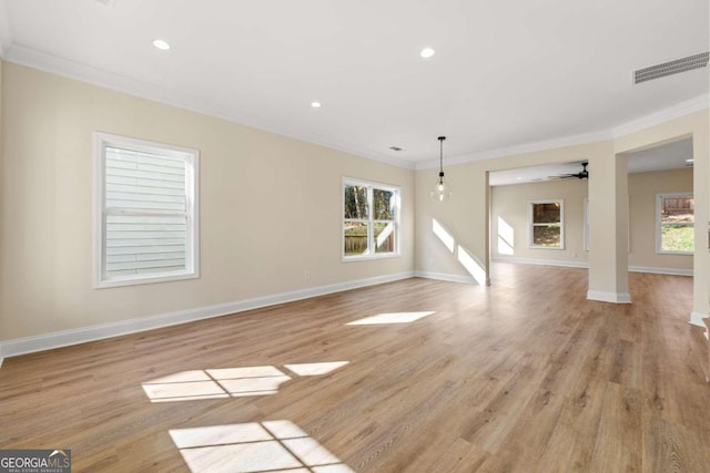 unfurnished living room featuring ceiling fan, light wood-type flooring, ornamental molding, and a wealth of natural light