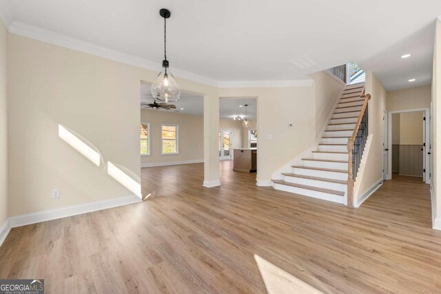 unfurnished living room with ceiling fan, light hardwood / wood-style floors, and ornamental molding