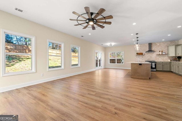 unfurnished living room featuring ceiling fan, a healthy amount of sunlight, and light hardwood / wood-style flooring