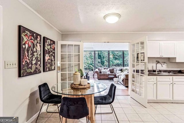 dining area featuring a textured ceiling, light tile patterned flooring, ornamental molding, and sink