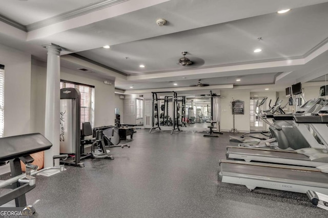 gym with ornate columns, ceiling fan, and a tray ceiling