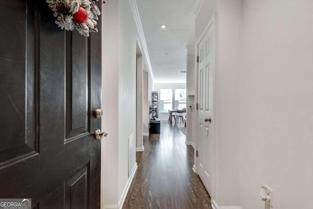 hall with dark wood-type flooring, ornamental molding, and a textured ceiling