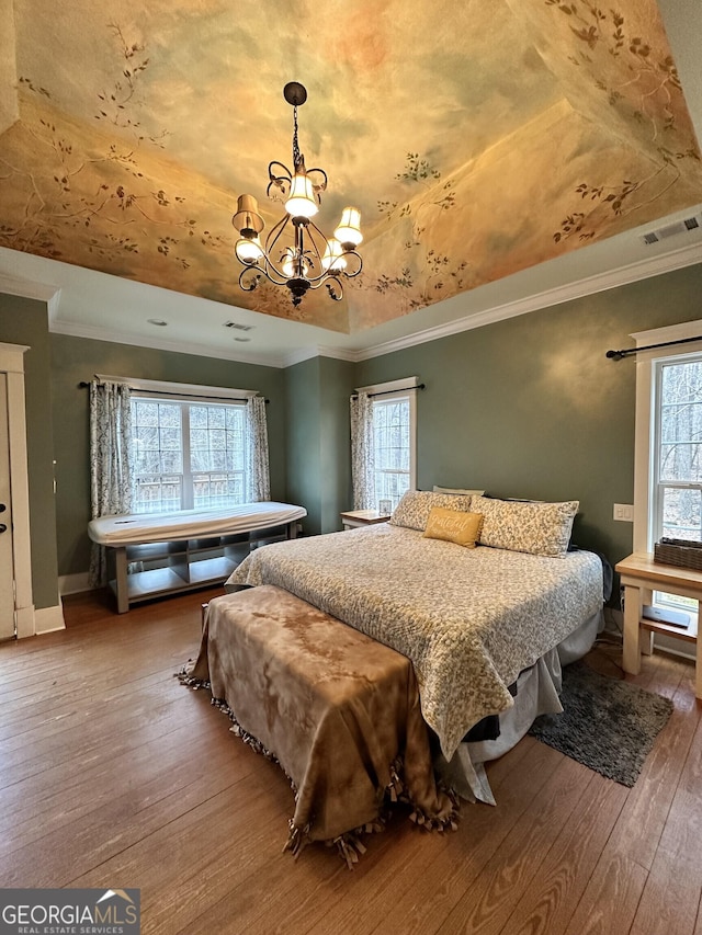 bedroom with hardwood / wood-style floors, an inviting chandelier, and ornamental molding