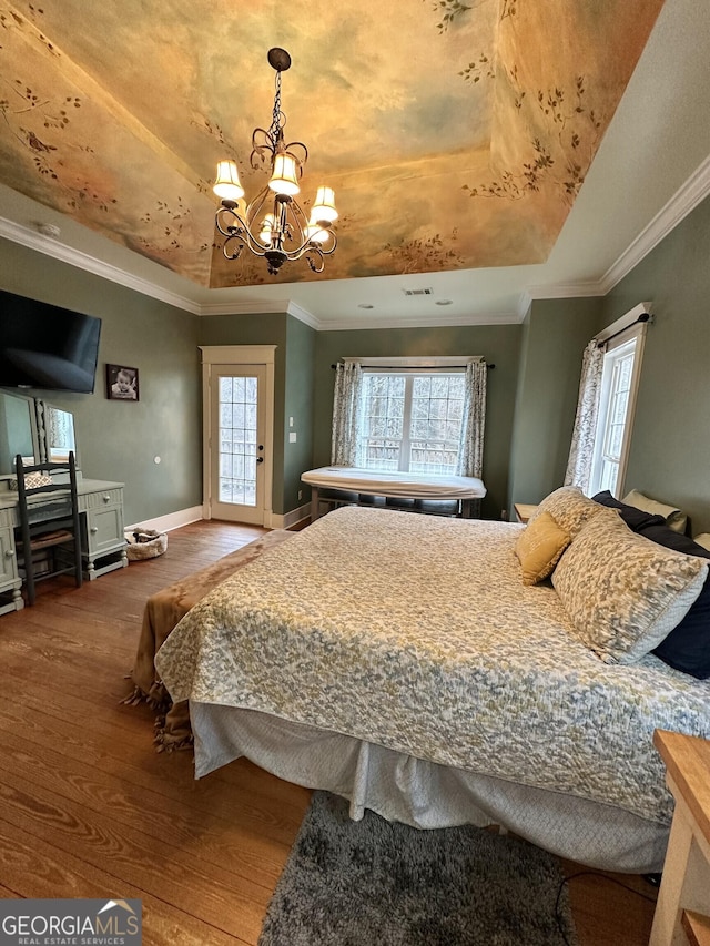 bedroom with a raised ceiling, wood-type flooring, multiple windows, and a chandelier