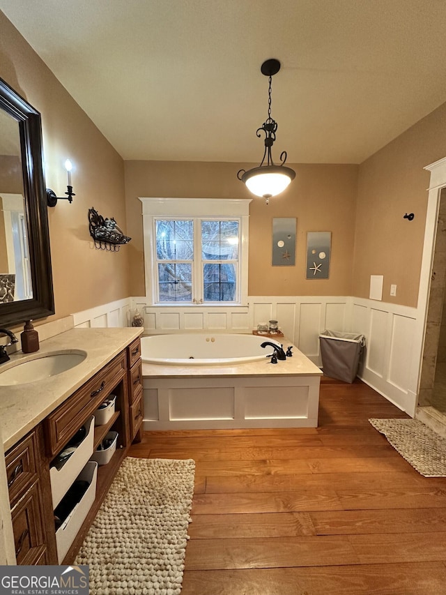 bathroom with hardwood / wood-style flooring, vanity, and a tub