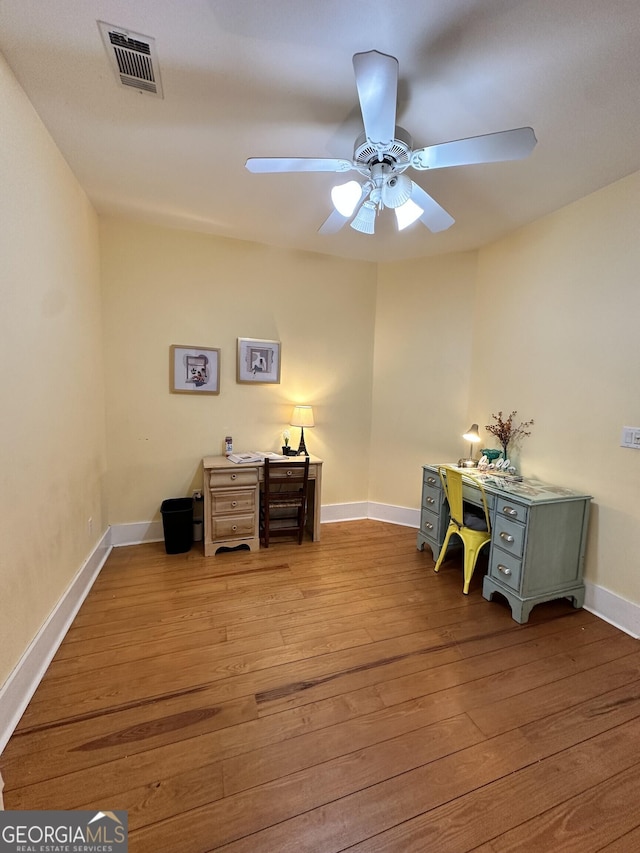 unfurnished office with ceiling fan and light wood-type flooring