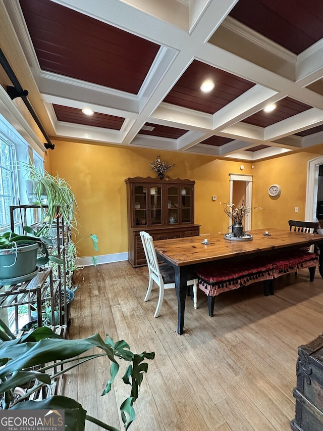 dining room featuring crown molding, light hardwood / wood-style flooring, beamed ceiling, and coffered ceiling