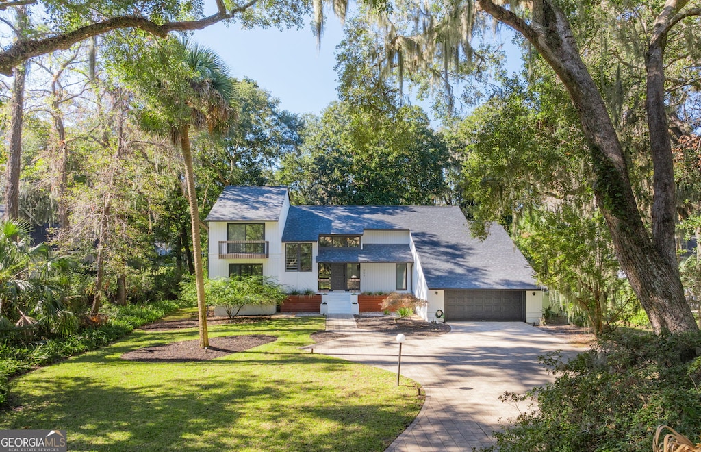 view of front facade with a balcony, a front yard, and a garage