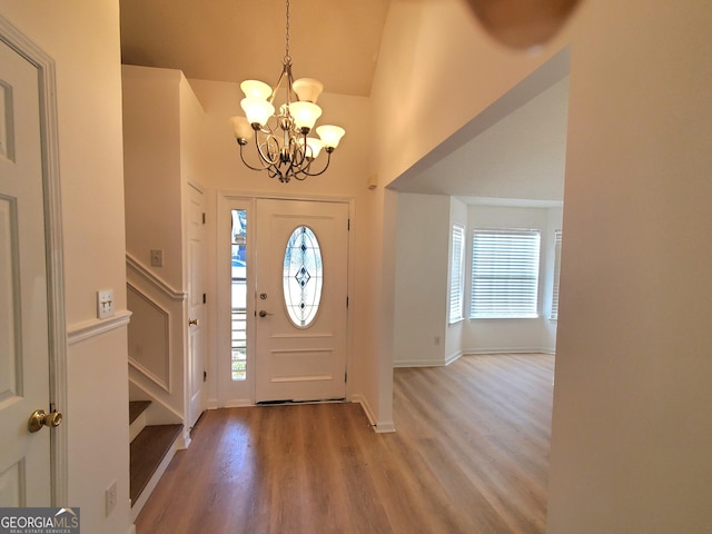 foyer with hardwood / wood-style flooring, a notable chandelier, a healthy amount of sunlight, and high vaulted ceiling