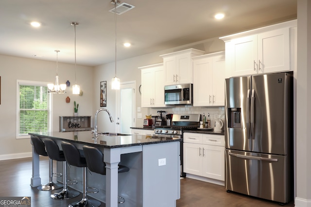 kitchen featuring white cabinets, sink, dark hardwood / wood-style floors, an island with sink, and appliances with stainless steel finishes