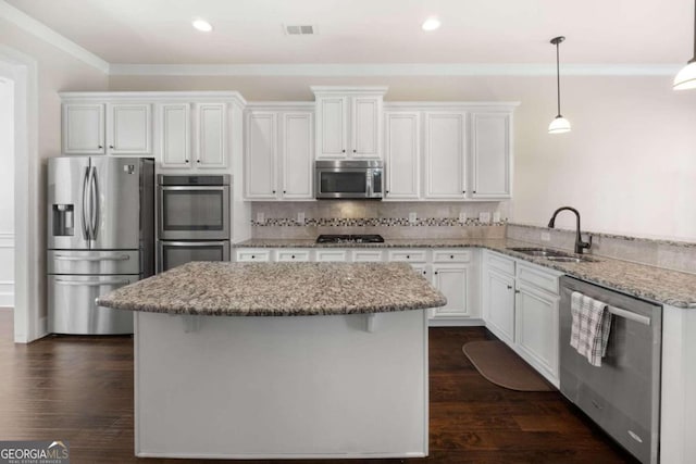 kitchen featuring appliances with stainless steel finishes, light stone counters, sink, white cabinetry, and hanging light fixtures