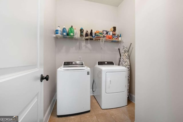 clothes washing area featuring light tile patterned floors and washer and dryer