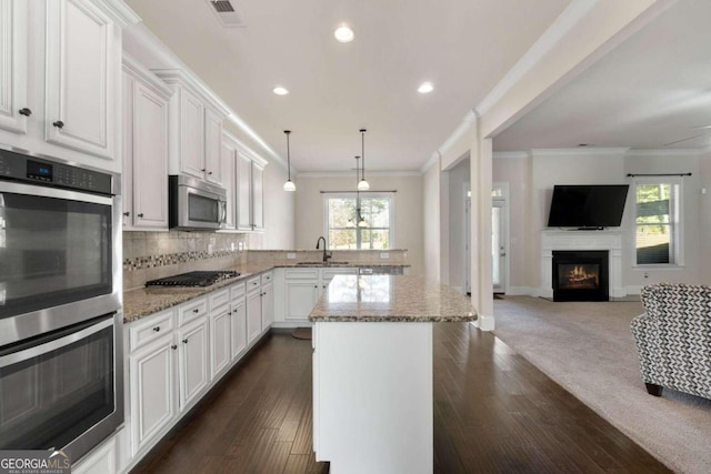 kitchen featuring dark wood-type flooring, white cabinets, hanging light fixtures, light stone counters, and stainless steel appliances