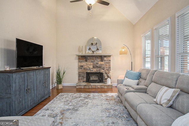 living room featuring ceiling fan, lofted ceiling, dark hardwood / wood-style flooring, and a wood stove