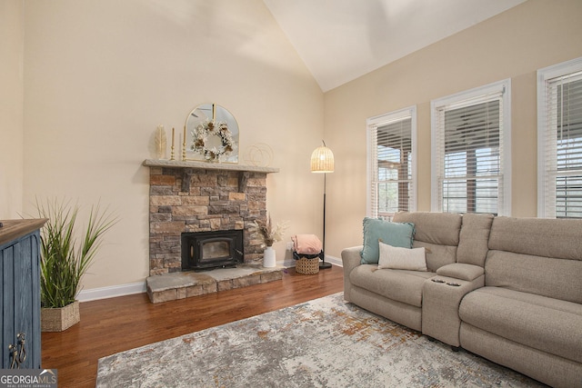 living room with vaulted ceiling, hardwood / wood-style floors, and a wood stove