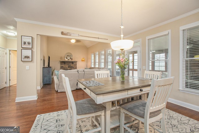 dining room with dark wood-type flooring, ornamental molding, and vaulted ceiling