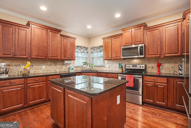 kitchen with sink, a center island, dark stone counters, and appliances with stainless steel finishes