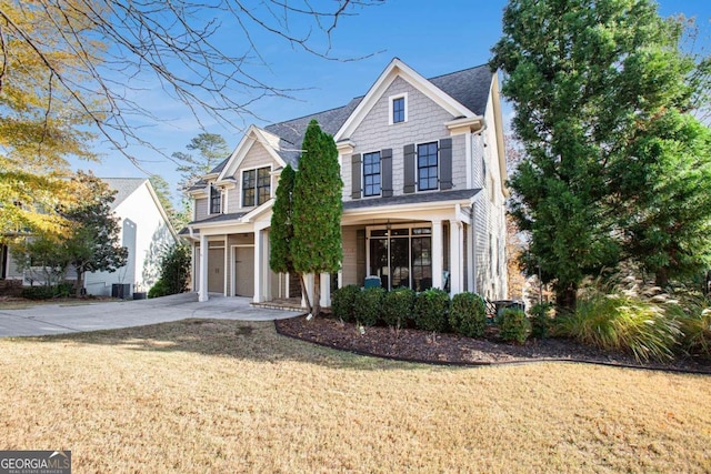 view of front of house featuring a garage, central air condition unit, and a front lawn