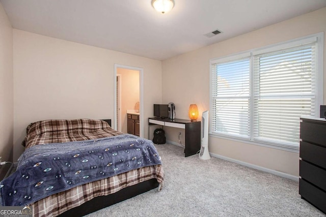 bedroom with multiple windows, ensuite bathroom, and light colored carpet