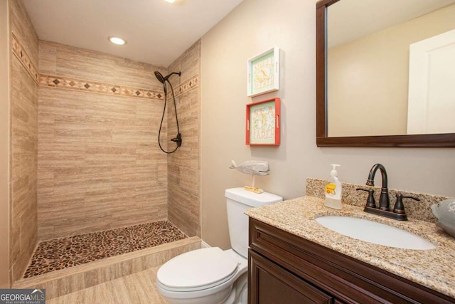 bathroom featuring tiled shower, vanity, and toilet