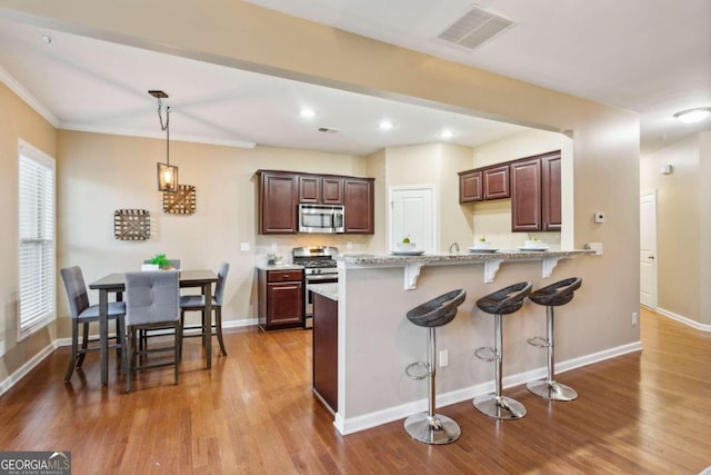 kitchen with a wealth of natural light, hanging light fixtures, light wood-type flooring, and appliances with stainless steel finishes