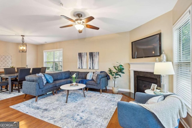 living room with ceiling fan with notable chandelier and wood-type flooring