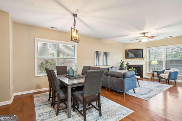 dining space featuring ceiling fan with notable chandelier and hardwood / wood-style flooring