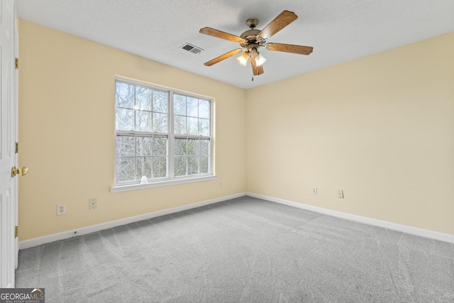 carpeted empty room with a ceiling fan, visible vents, a textured ceiling, and baseboards