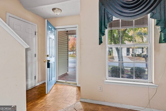 entryway featuring a healthy amount of sunlight, a textured ceiling, and light parquet floors