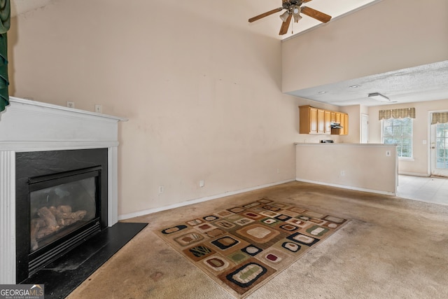 living room with ceiling fan, light colored carpet, and a textured ceiling