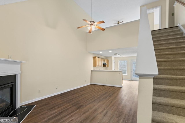 unfurnished living room featuring dark wood-style floors, stairs, baseboards, and a glass covered fireplace