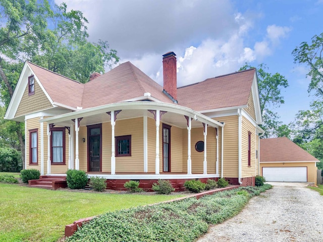 farmhouse with an outbuilding, covered porch, a front yard, and a garage