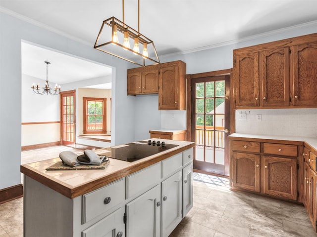 kitchen with black electric stovetop, decorative light fixtures, an inviting chandelier, and a healthy amount of sunlight