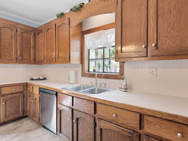 kitchen with tile countertops, dishwasher, backsplash, crown molding, and sink