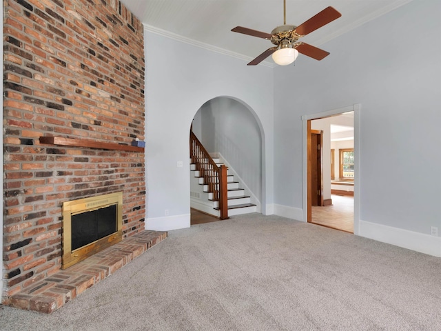 unfurnished living room featuring ceiling fan, a fireplace, carpet floors, and ornamental molding