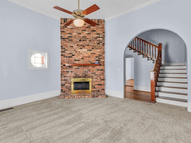 unfurnished living room with ceiling fan, a fireplace, carpet, and ornamental molding