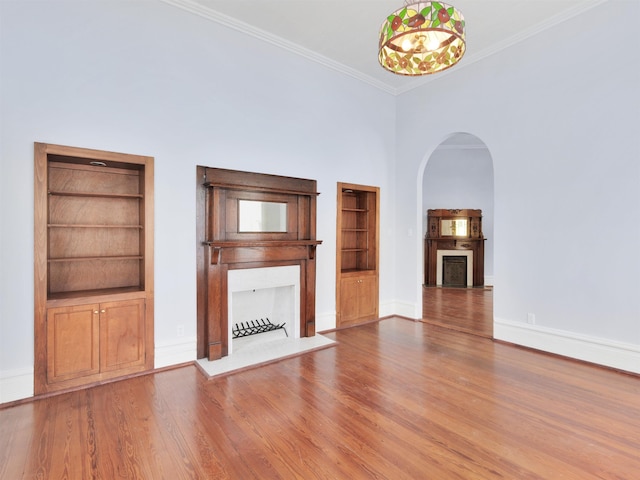 unfurnished living room featuring wood-type flooring, ornamental molding, and a towering ceiling