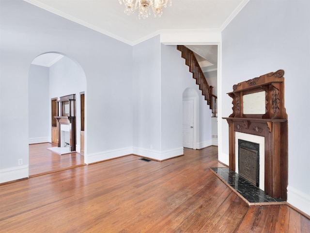 unfurnished living room featuring hardwood / wood-style flooring, ornamental molding, and a notable chandelier