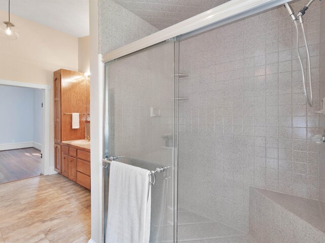 bathroom with crown molding, a shower with door, vanity, and wood-type flooring