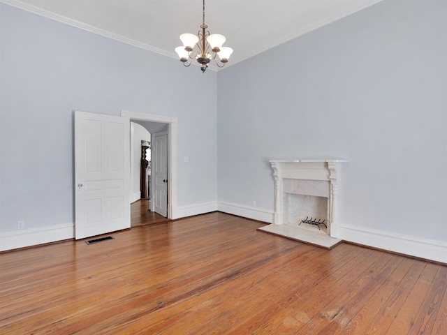 unfurnished living room with a chandelier, wood-type flooring, crown molding, and a high end fireplace