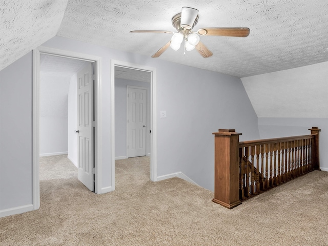 bonus room featuring a textured ceiling, light colored carpet, and lofted ceiling