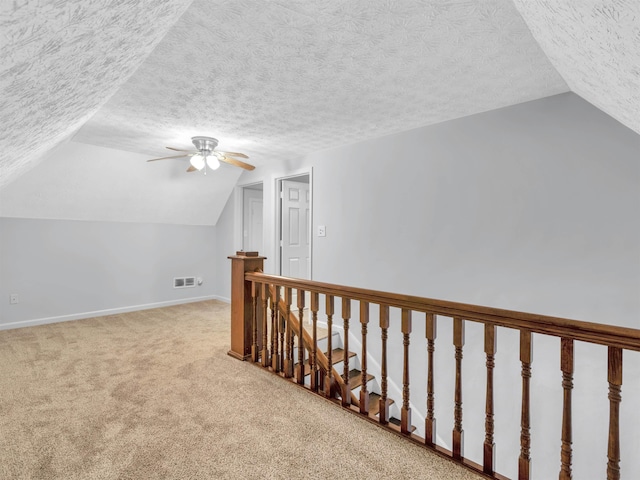 additional living space with vaulted ceiling, ceiling fan, carpet flooring, and a textured ceiling