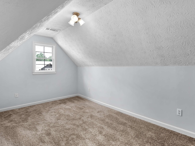 additional living space with vaulted ceiling, carpet floors, and a textured ceiling