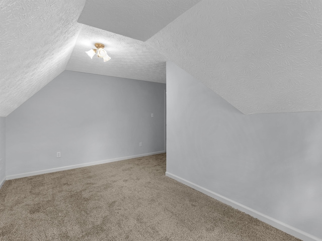 additional living space with carpet flooring, a textured ceiling, and vaulted ceiling