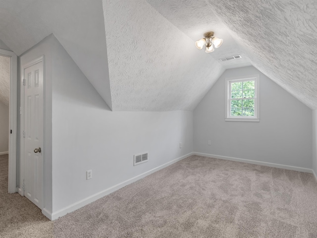 bonus room featuring carpet, lofted ceiling, and a textured ceiling